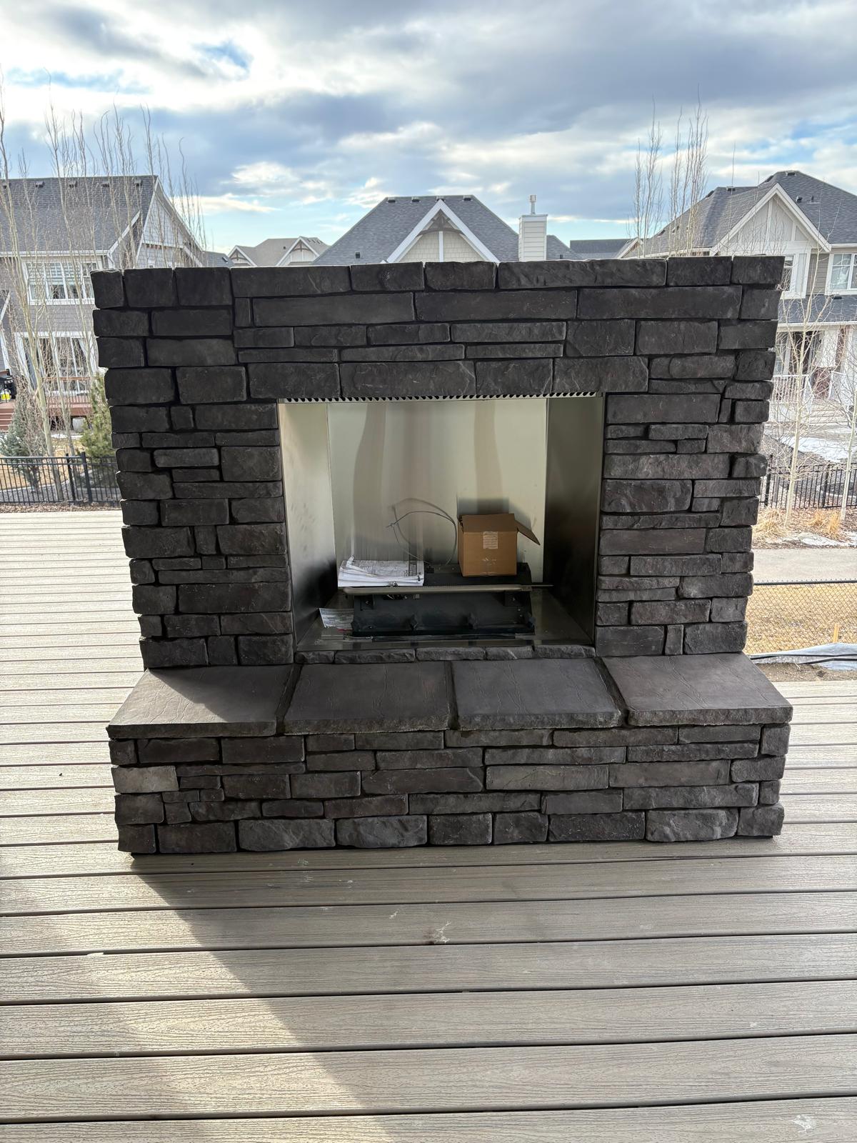 Outdoor stacked-stone fireplace on a backyard deck