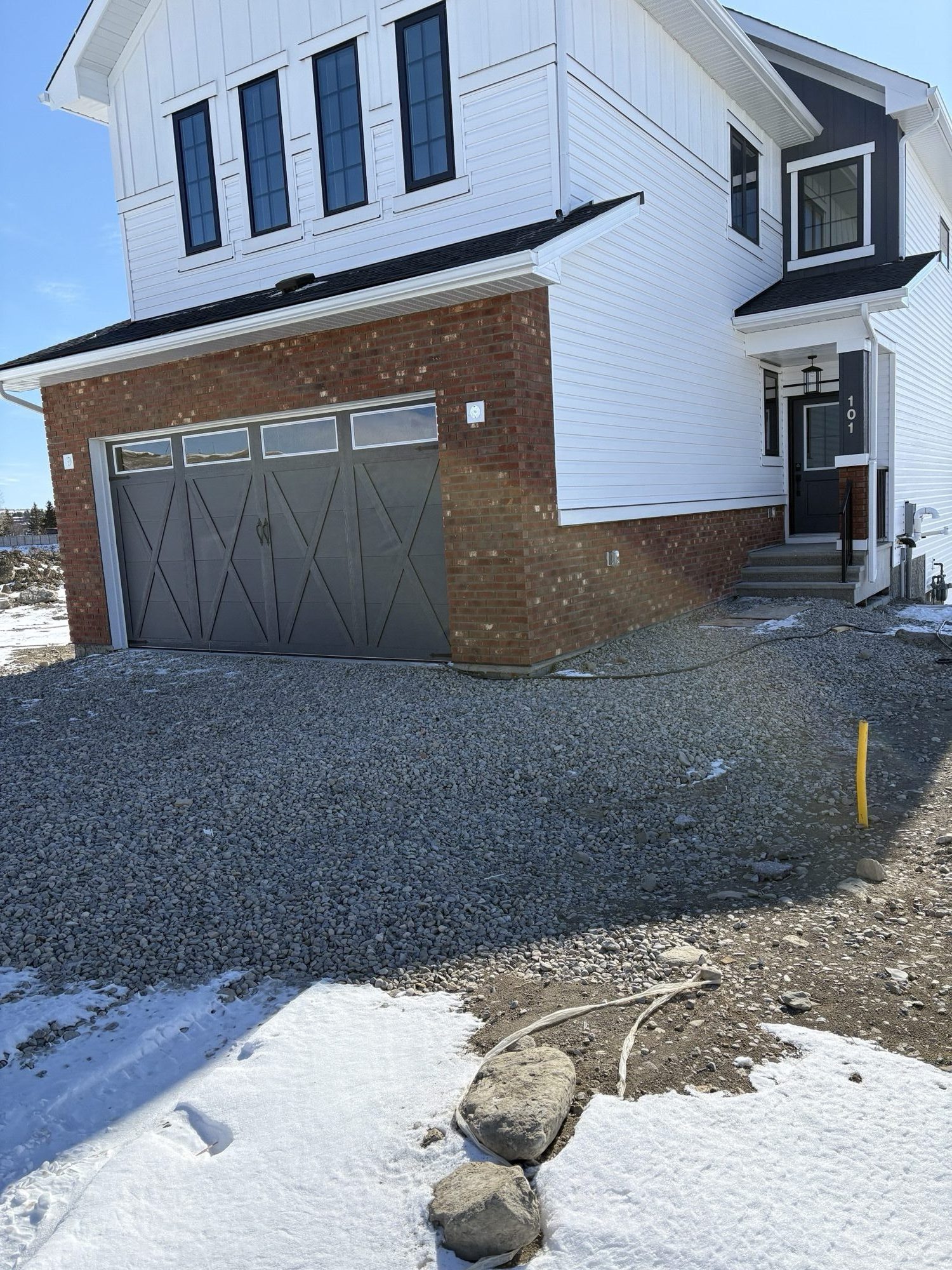 White two-storey home with red brick garage façade