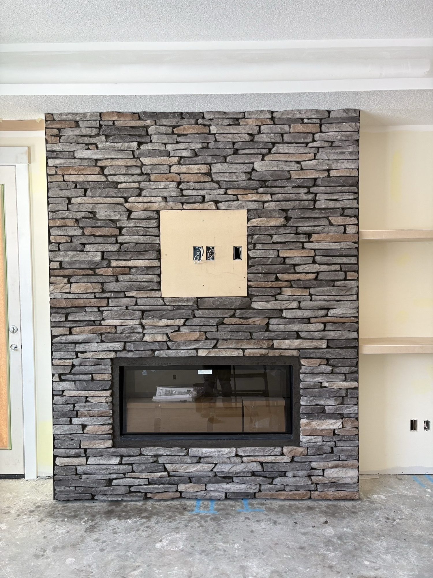 Floor-to-ceiling stacked stone fireplace surround during install