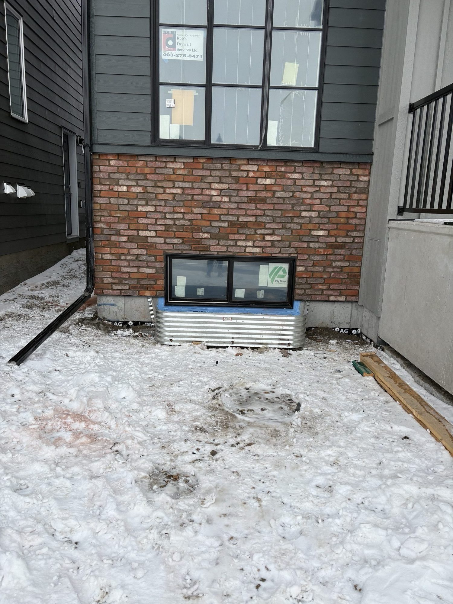 Red brick side-yard wall between two homes with a basement window