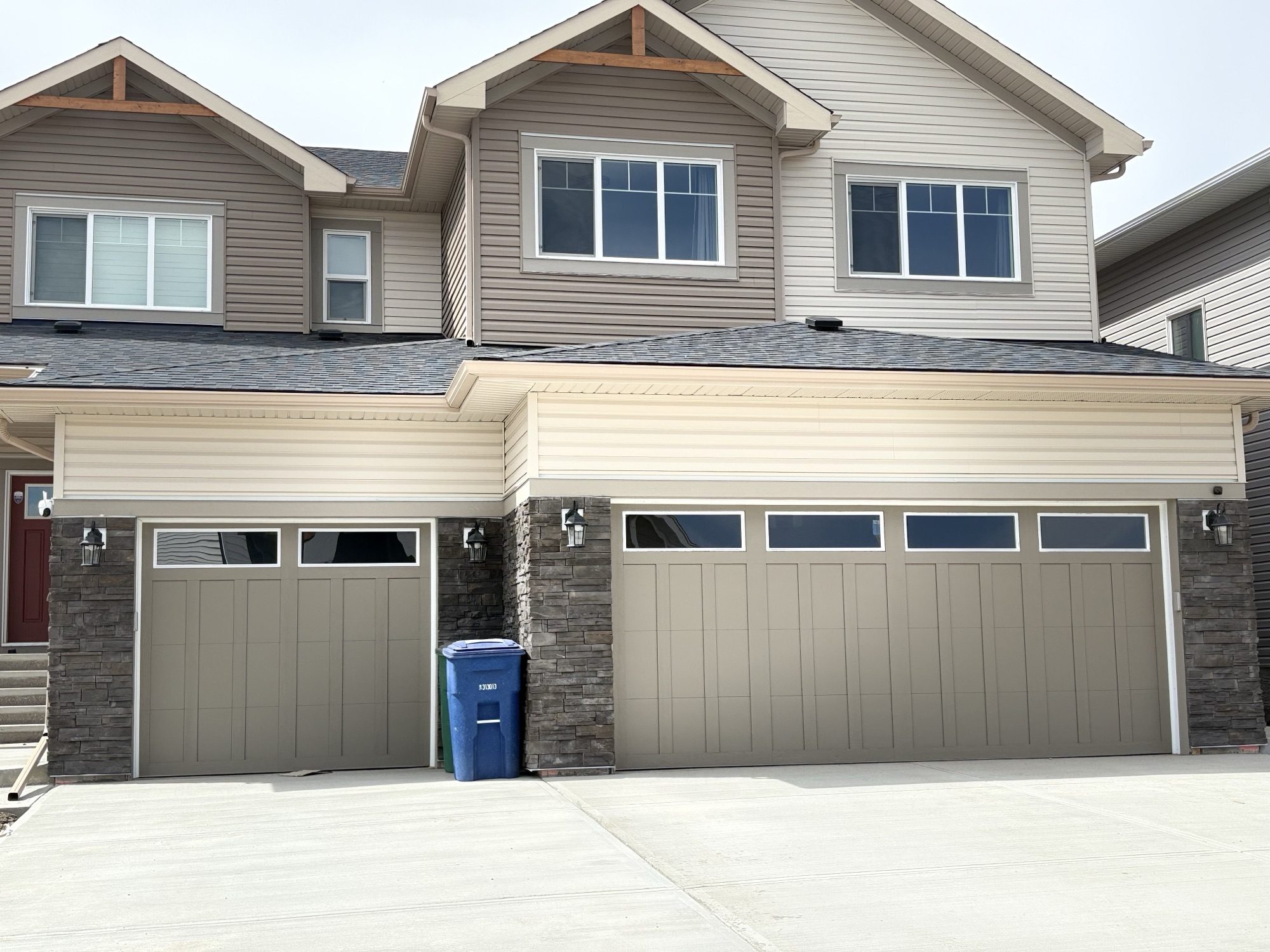 Two-storey home with stacked stone garage façade and double doors